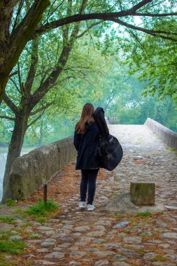Genç kız naure içinde yürürken gitar çantası taşıyor. Bayan gitarist gitaristle seyahat eder ve güzel manzaranın tadını çıkarır.