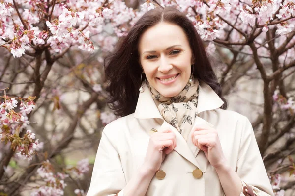 Porträt einer schönen jungen Frau vor rosa Kirschblüten im Frühling — Stockfoto