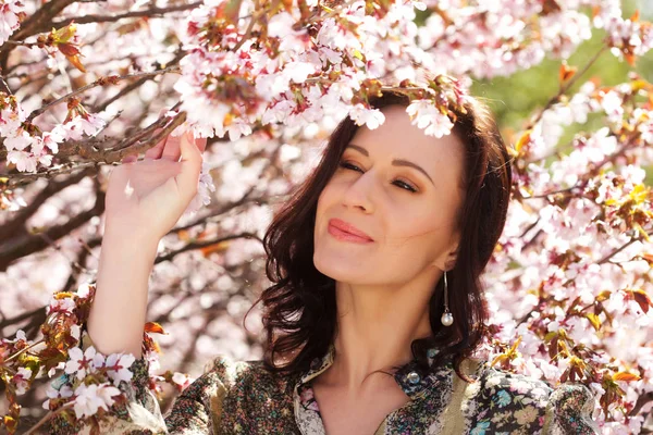 Young woman on a background of pink cherry blossoms in spring, lifestyle concept — Stock Photo, Image