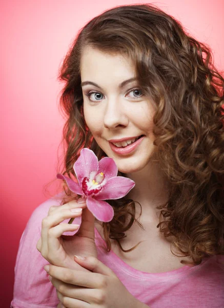 Vacker lycklig kvinna med orkidé blomma över rosa bakgrund — Stockfoto