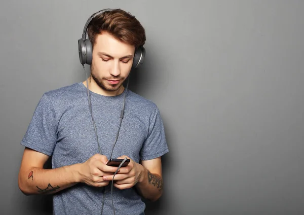 Junger Mann mit Kopfhörer und Handy in der Hand — Stockfoto