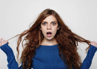 Çok güzel kadın kıvırcık saçlı kamera olmasının seyir heyecanlı ve mutlu yüz ifadesi, boş stüdyo duvar karşı.