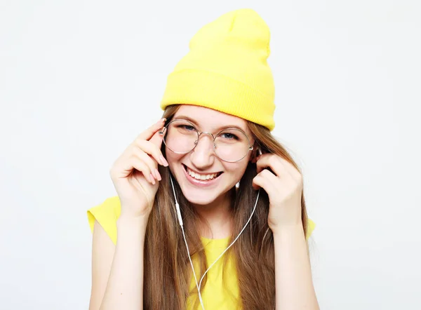 Moda menina muito legal em fones de ouvido ouvir música usando chapéu amarelo e t-shirt — Fotografia de Stock