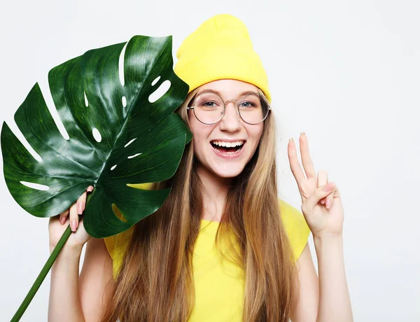 Lifestyle, emotie en mensen concept: mooie jongedame dragen gele casual kleding, houden van blad van monstera — Stockfoto