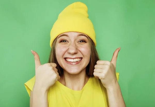 Lifestyle, emotion and people concept: Happy woman wearing yellow clothes giving thumb up — Stock Photo, Image