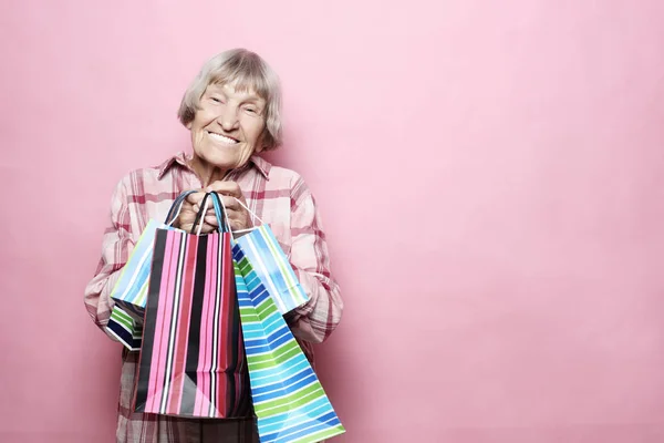 Gelukkig grootmoeder met boodschappentassen op roze achtergrond. Levensstijl en mensen concept. — Stockfoto