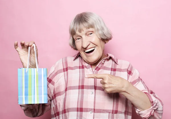 生活方式和人的概念: 愉快的资深妇女与购物袋在粉红色背景下 — 图库照片