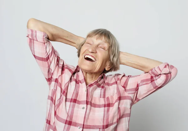Happy Grandma in a pink shirt crossed her arms over her head — Stock Photo, Image
