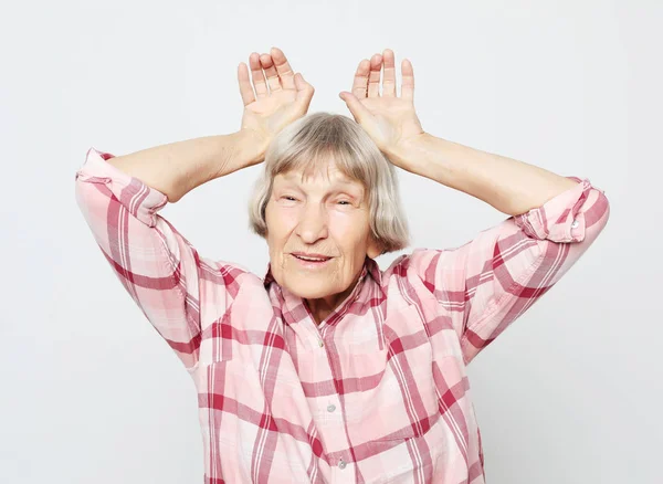 Lifestyle, emotie en mensen concept: leeftijd grootmoeder met geschokt gezicht. Portret van grootmoeder met roze shirt. — Stockfoto