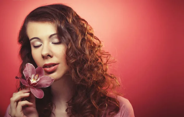 Vacker lycklig kvinna med orkidé blomma över rosa bakgrund — Stockfoto