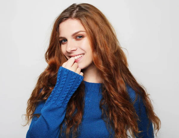 Pretty beautiful woman with curly hair looking at camera having excited and happy facial expression, against blank studio wall. — Stock Photo, Image