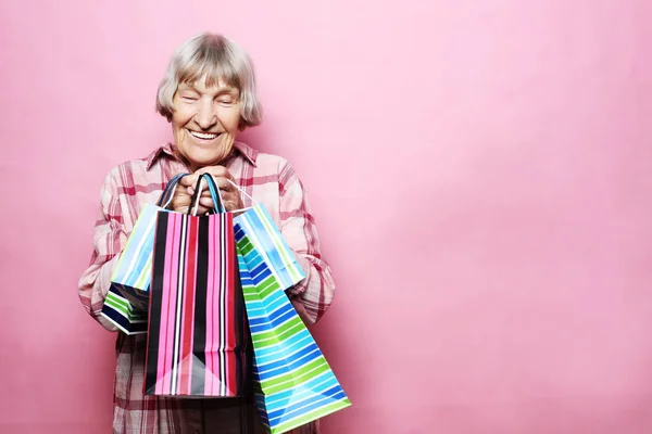 快乐的祖母与购物袋在粉红色的背景。生活方式和人的概念. — 图库照片