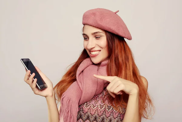 Lifestyle and people concept: Smiling woman is pointing on smartphone — Stock Photo, Image