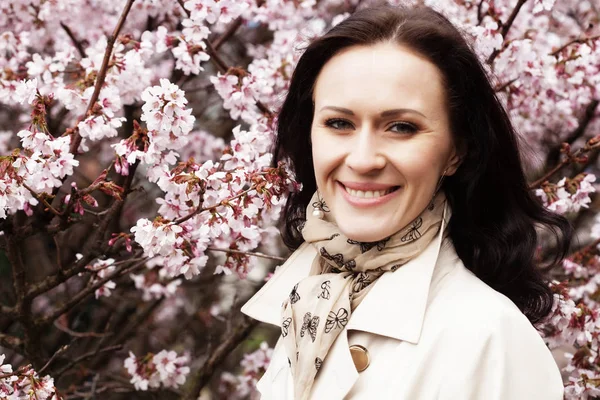 Portrait of a beautiful young woman on a background of pink cherry blossoms in spring, — Stock Photo, Image