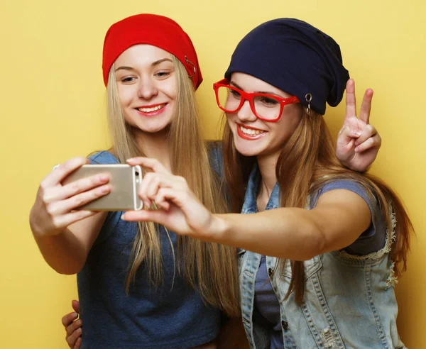 Deux jeunes filles hipster amis prenant selfie sur fond jaune — Photo