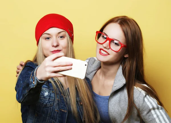 Duas adolescentes amigas em roupa hipster fazem selfie em um telefone — Fotografia de Stock