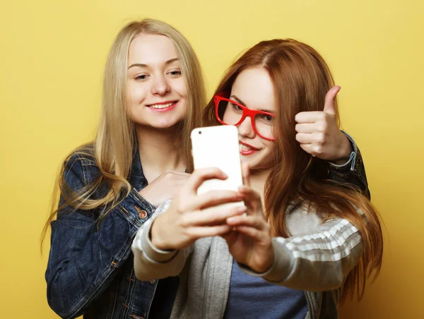 Twee tiener meisjes vrienden in hipster outfit maken selfie op een telefoon — Stockfoto