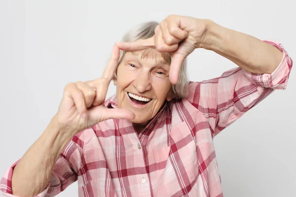 Lifestyle, emotie en mensen concept: leeftijd grootmoeder met geschokt gezicht. Portret van grootmoeder met roze shirt. — Stockfoto