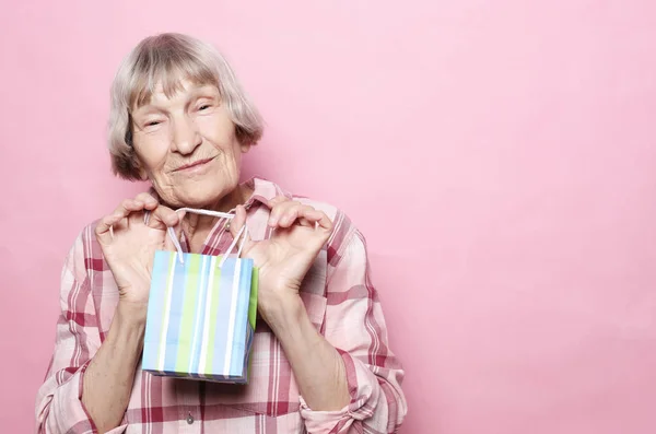 Koncepcja życia i ludzi: Happy senior kobieta z torbą na zakupy na różowym tle — Zdjęcie stockowe