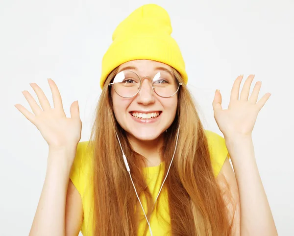 Moda menina muito legal em fones de ouvido ouvir música usando chapéu amarelo e t-shirt sobre fundo branco — Fotografia de Stock