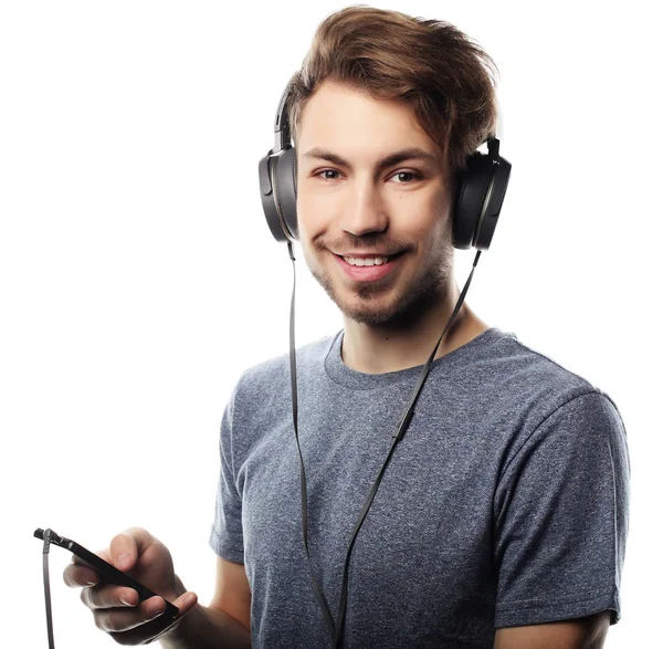 Mann hält Handy in der Hand und hört Musik über weißen Rucksack — Stockfoto