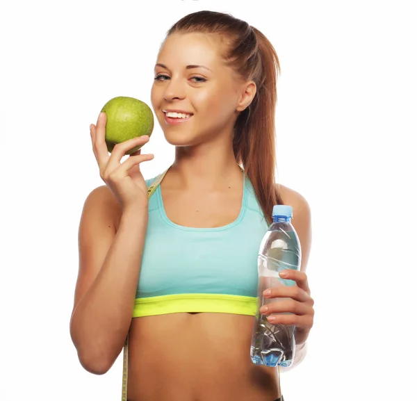 Deporte, dieta, salud y concepto de personas: Joven mujer alegre en ropa deportiva con manzana y una botella de agua, aislada sobre fondo blanco —  Fotos de Stock