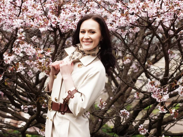 Portrait d'une belle jeune femme sur fond de fleurs de cerisier rose au printemps — Photo