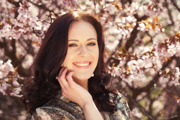 Portrait of a beautiful young woman on a background of pink cherry blossoms in spring — Stock Photo, Image