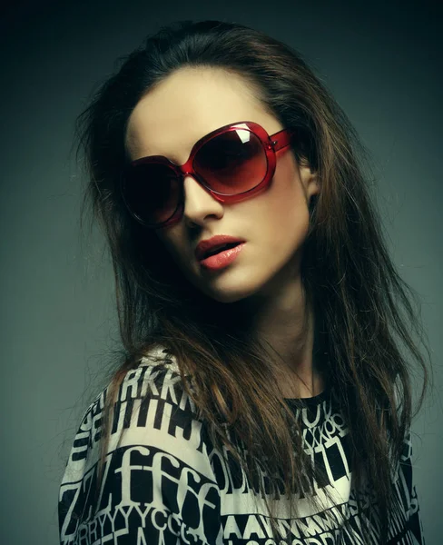 Mooie mode vrouw dragen zonnebril over grijze achtergrond — Stockfoto