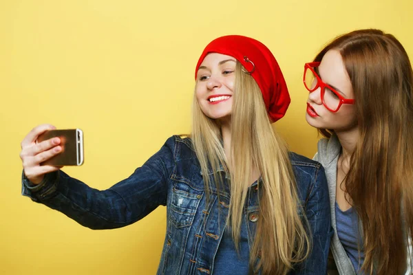Две подружки-подростки в хипстерском костюме делают селфи по телефону — стоковое фото