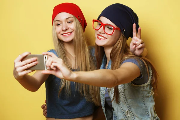 İki genç hippi kız arkadaş sarı arka planda selfie çekiyorlar. — Stok fotoğraf