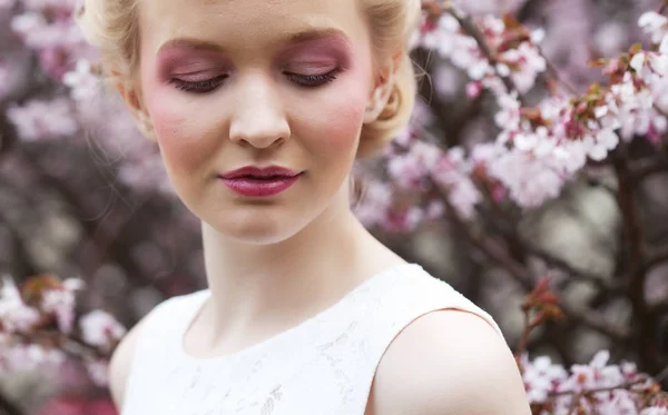 Portrét krásné mladé blondýny na pozadí růžových třešňových květů na jaře — Stock fotografie