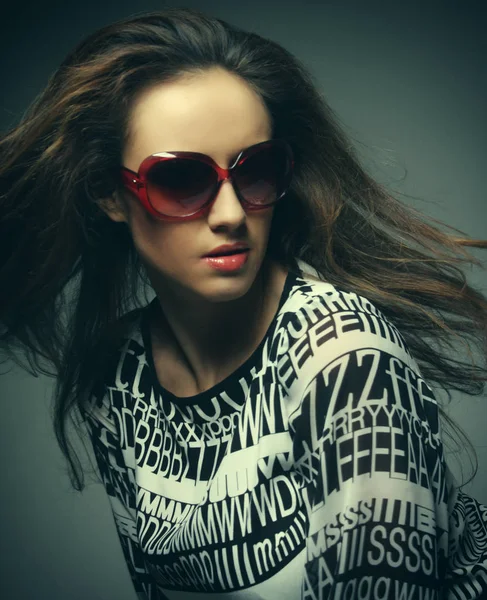 Hermosa mujer de moda con gafas de sol sobre fondo gris — Foto de Stock