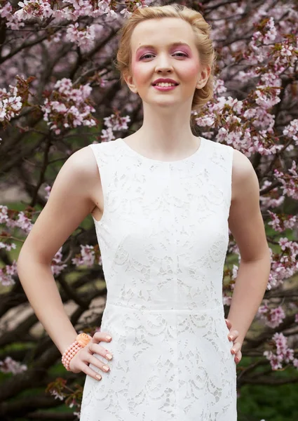 Portrét krásné mladé blondýny na pozadí růžových třešňových květů na jaře — Stock fotografie