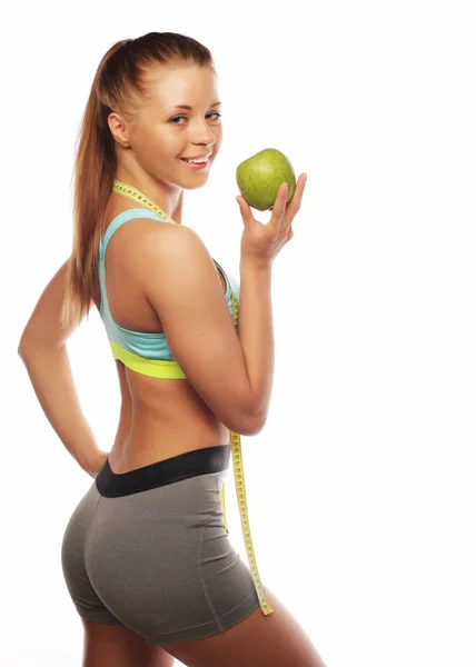 Cheerful woman in sports wear with apple and a bottle of water, isolated over white background — Stock Photo, Image
