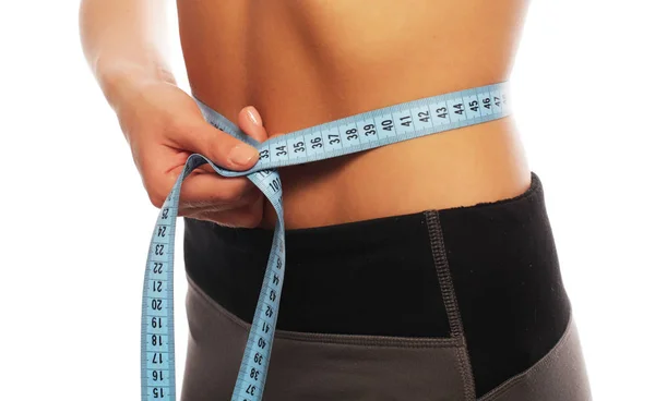 Close-up of a woman in sportswear measuring her waist over white background — Stock Photo, Image