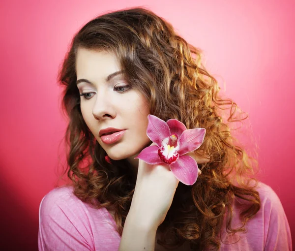 Hermosa mujer feliz con flor de orquídea sobre fondo rosa —  Fotos de Stock