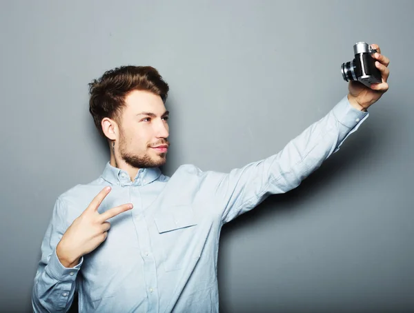 Guapo joven sosteniendo la cámara y haciendo selfie — Foto de Stock