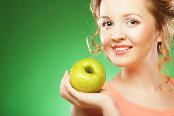 金髪の女性は緑の背景に青リンゴを食べる — ストック写真