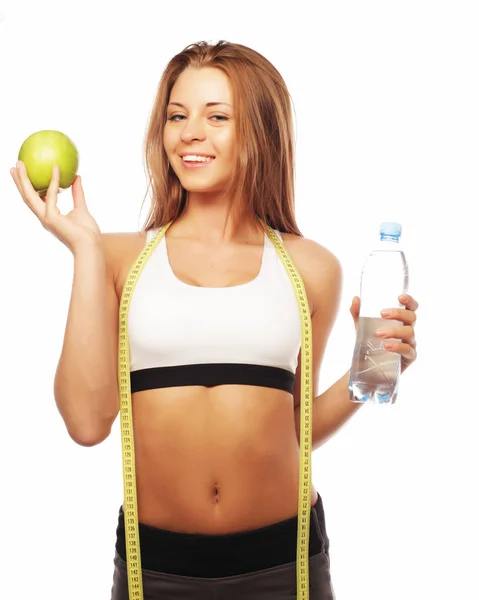 Spor, diyet, sağlık ve insan kavramı: Spor genç neşeli kadın elma ve su şişesi ile giyim, beyaz arka plan üzerinde izole — Stok fotoğraf