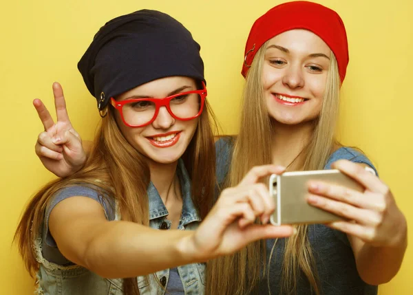 Dwa młody hipster dziewczyny przyjaciele biorąc selfie na żółtym tle — Zdjęcie stockowe