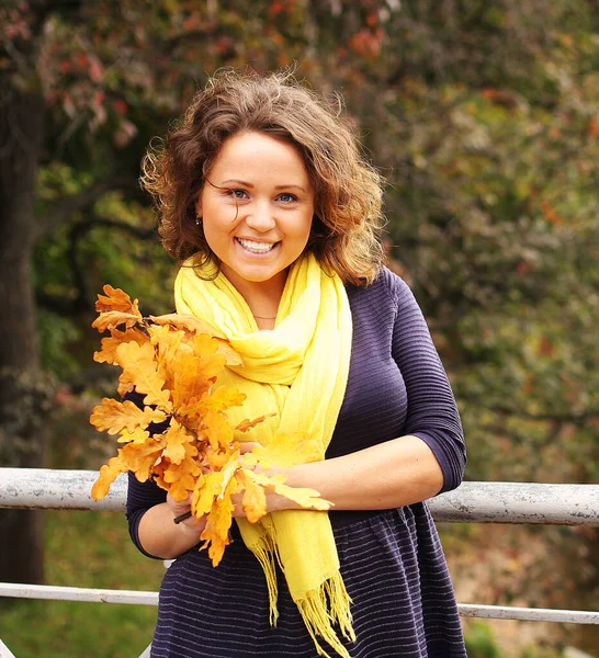 Young woman with autumn leaves in park — Stock Photo, Image