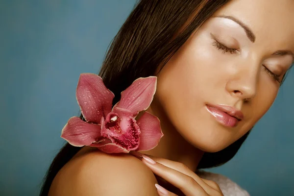 Mujer con flor de orquídea sobre fondo azul — Foto de Stock