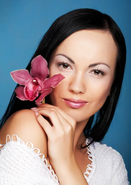 Mujer con flor de orquídea sobre fondo azul — Foto de Stock