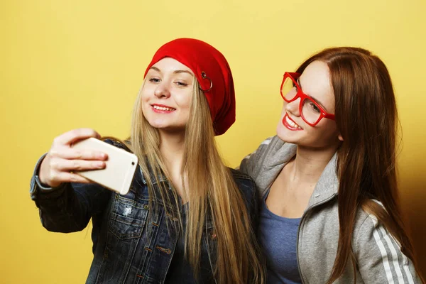 Två tonårsflickor vänner i hipster outfit gör selfie på en telefon — Stockfoto