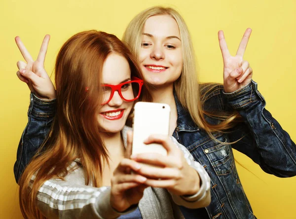 Dos amigas adolescentes en traje hipster hacen selfie en un teléfono —  Fotos de Stock