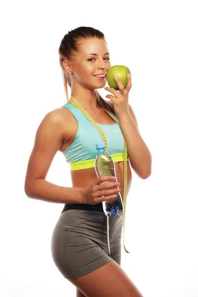 Młoda pogodna kobieta w sportowym stroju z zielonym jabłkiem na białym tle — Zdjęcie stockowe