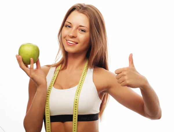 Жінка в спортивному одязі з зеленим яблуком на білому тлі — стокове фото