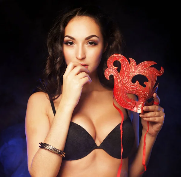 Junge sexy brünette Frau, trägt Dessous, hält rote Maske — Stockfoto