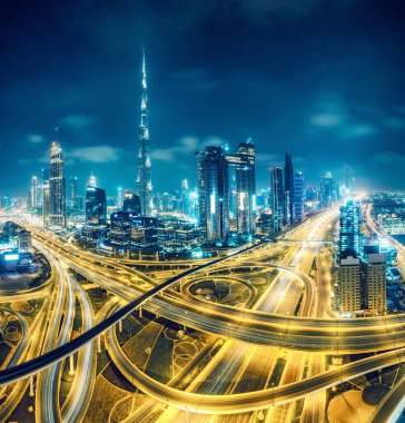 Geceleri Dubai'de. Otoyollar ve gökdelenler üzerinde manzara hava görünümü.